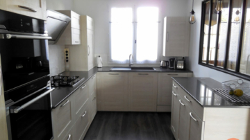 Photo d'une cuisine avec verrière, mobilier bois clair, plan de travail pierre gris anthracite, parquet gris foncé, crédence carrelage métro