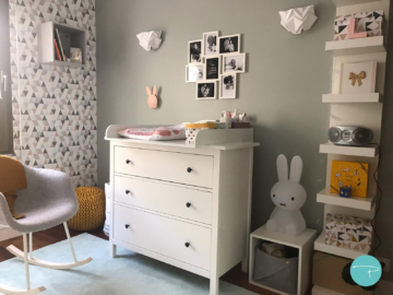 Photo chambre d'enfant papier peint origami géométrique, pouf tricoté jaune, chaise à bascule grise, table à langer Ikea, appliques murales origami, lampe Miffy