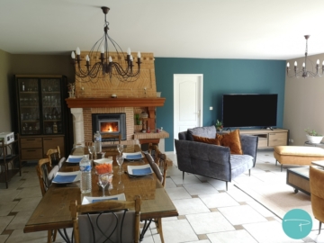 Photo d'un salon et d'une salle à manger avec une table à manger style campagne, canapé velours ocre, fauteuil velours gris anthracite et papier peint bleu canard