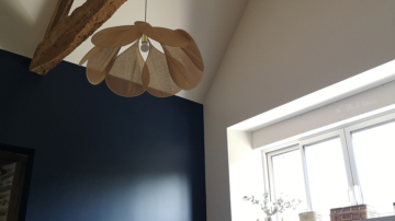 Photo d'une chambre parentale avec lit gris, mur bleu foncé, poutre apparente et suspension Pale de Georges