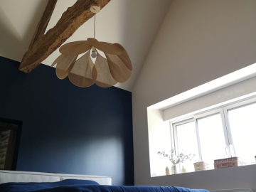 Photo d'une chambre parentale avec lit gris, mur bleu foncé, poutre apparente et suspension Pale de Georges