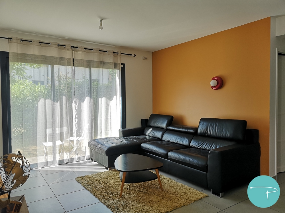 Photo après un conseil couleur d'un salon avec mur jaune ocre et applique murale rouge