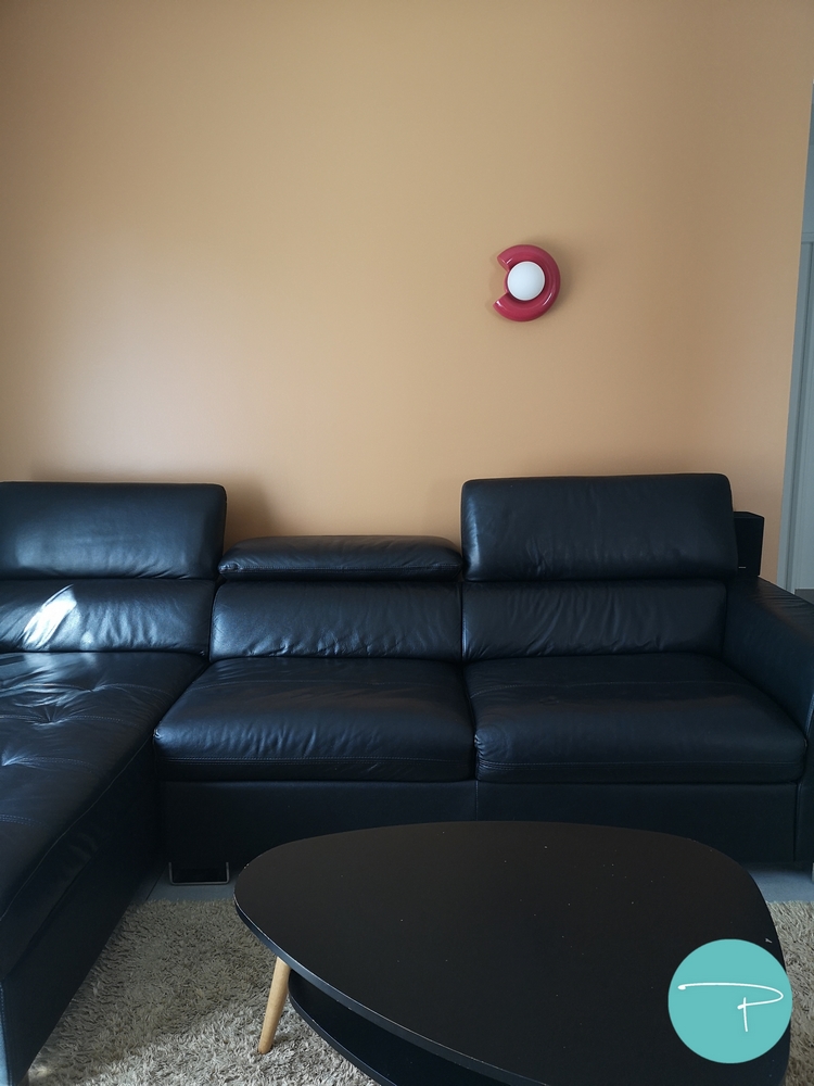 Photo après un conseil couleur d'un salon avec mur jaune ocre et applique murale rouge