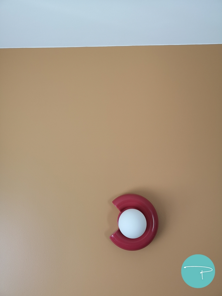Photo après un conseil couleur d'un salon avec mur jaune ocre et applique murale rouge