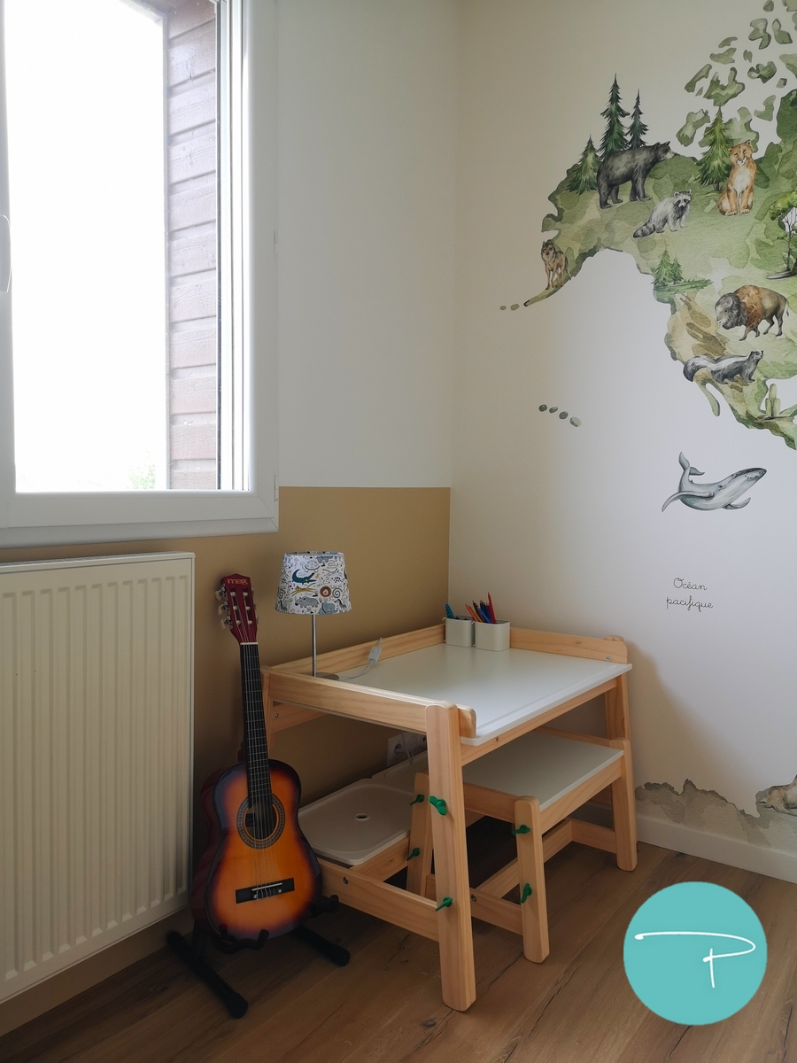 Chambre d’enfant décorée à Vitré autour d’une mappemonde panoramique illustrée. Une ambiance douce, naturelle et ludique, avec du mobilier en bois clair, des rangements pratiques et un univers inspiré du voyage, pensé pour stimuler l’imaginaire tout en conservant une pièce lumineuse et évolutive.