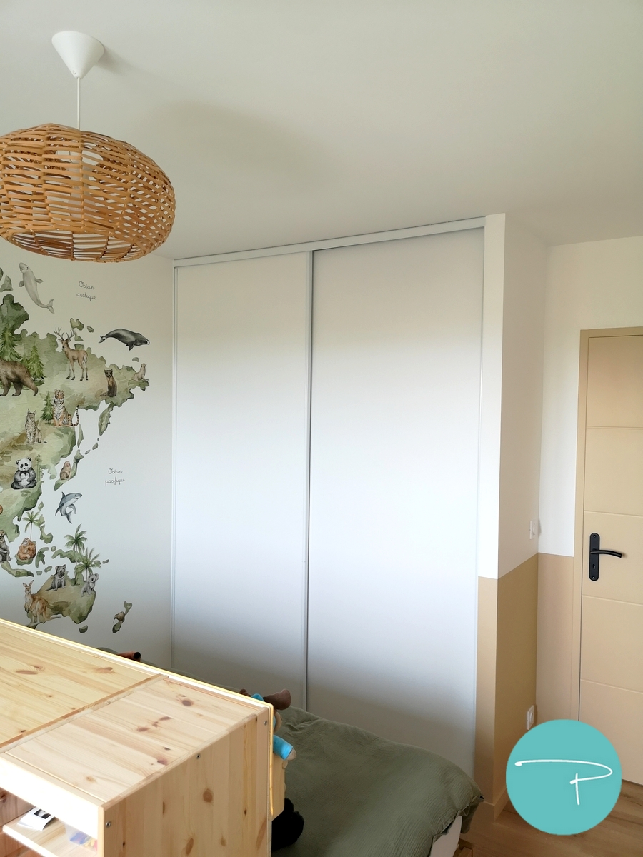 Chambre d’enfant décorée à Vitré autour d’une mappemonde panoramique illustrée. Une ambiance douce, naturelle et ludique, avec du mobilier en bois clair, des rangements pratiques et un univers inspiré du voyage, pensé pour stimuler l’imaginaire tout en conservant une pièce lumineuse et évolutive.