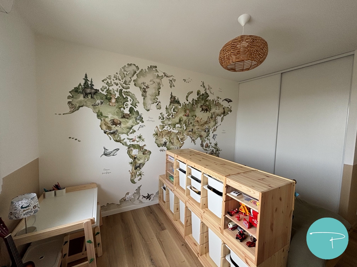 Chambre d’enfant décorée à Vitré autour d’une mappemonde panoramique illustrée. Une ambiance douce, naturelle et ludique, avec du mobilier en bois clair, des rangements pratiques et un univers inspiré du voyage, pensé pour stimuler l’imaginaire tout en conservant une pièce lumineuse et évolutive.